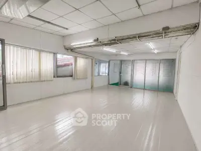 Spacious and bright interior room with large windows and modern flooring, ideal for office or studio space.