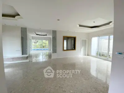 Spacious open-plan living area with large windows and marble flooring