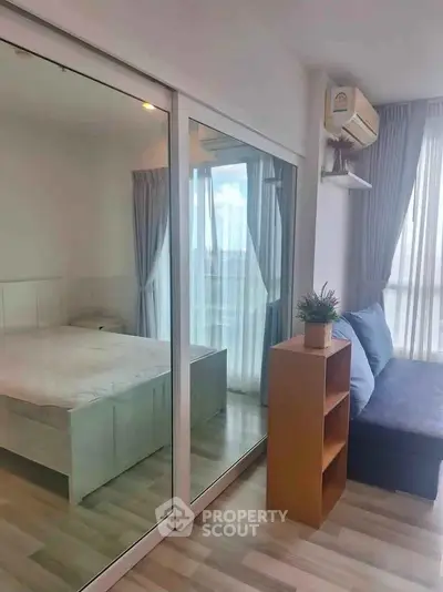 Modern bedroom with mirrored closet and cozy seating area in a bright apartment.