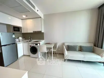 Modern open-plan kitchen and living room with sleek appliances and cozy seating area.
