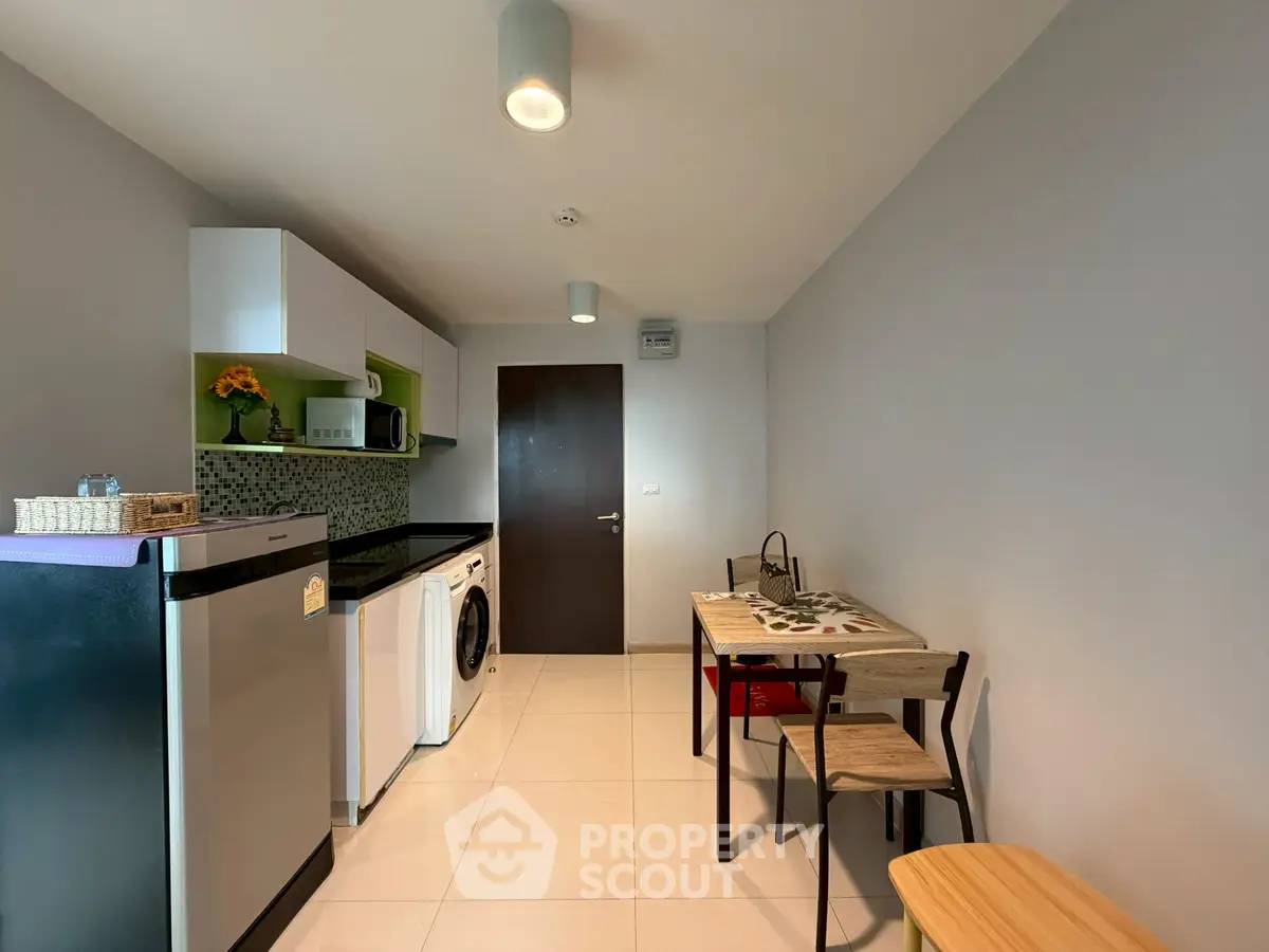 Modern kitchen with sleek appliances and dining area in compact layout.