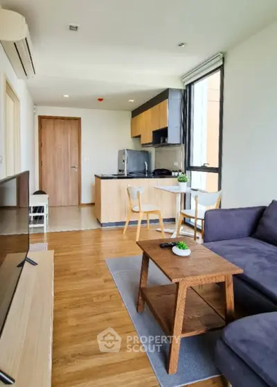 Modern open-plan living room with kitchen, featuring sleek wooden flooring and contemporary furniture.