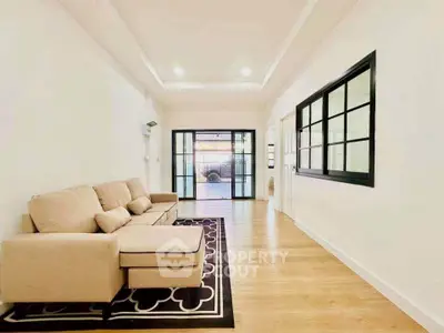 Spacious living room with modern beige sofa and stylish black-framed windows.