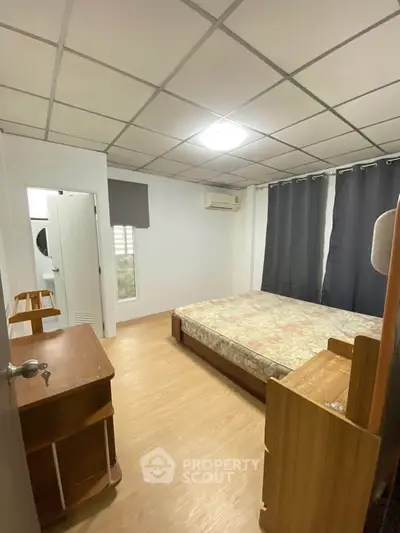 Cozy bedroom with wooden furniture and large window for natural light.