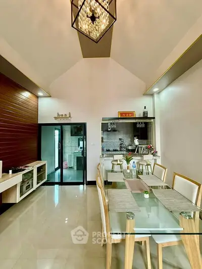 Elegant dining area with glass table and modern kitchen in open layout design