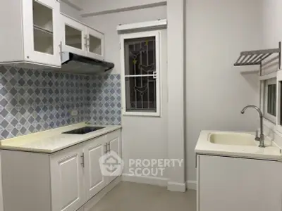 Charming kitchen with modern cabinets and stylish backsplash in cozy apartment.