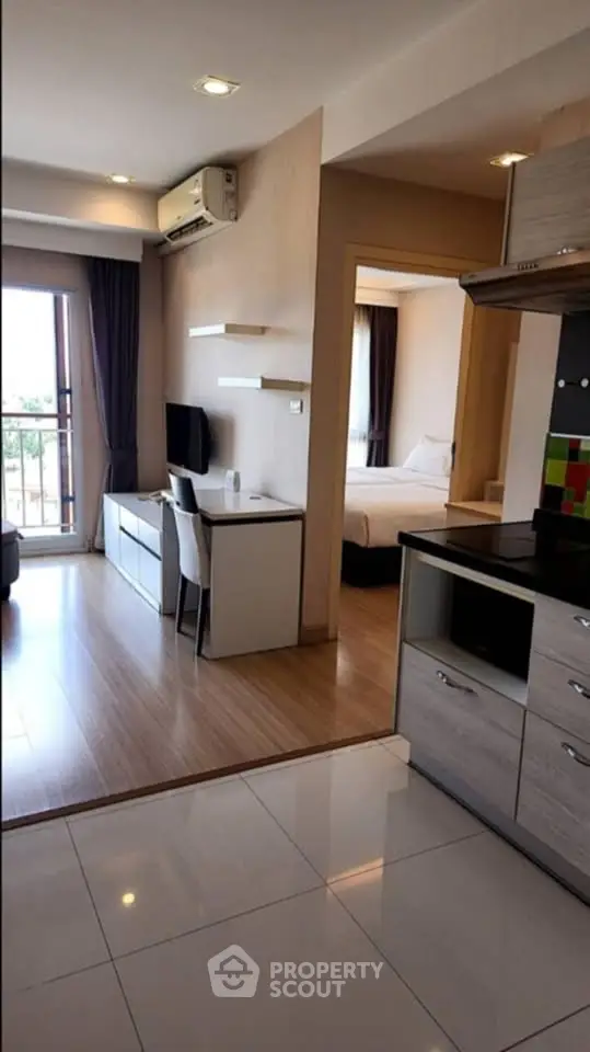 Modern open-plan apartment with sleek kitchen and cozy living area, featuring large windows and stylish decor.