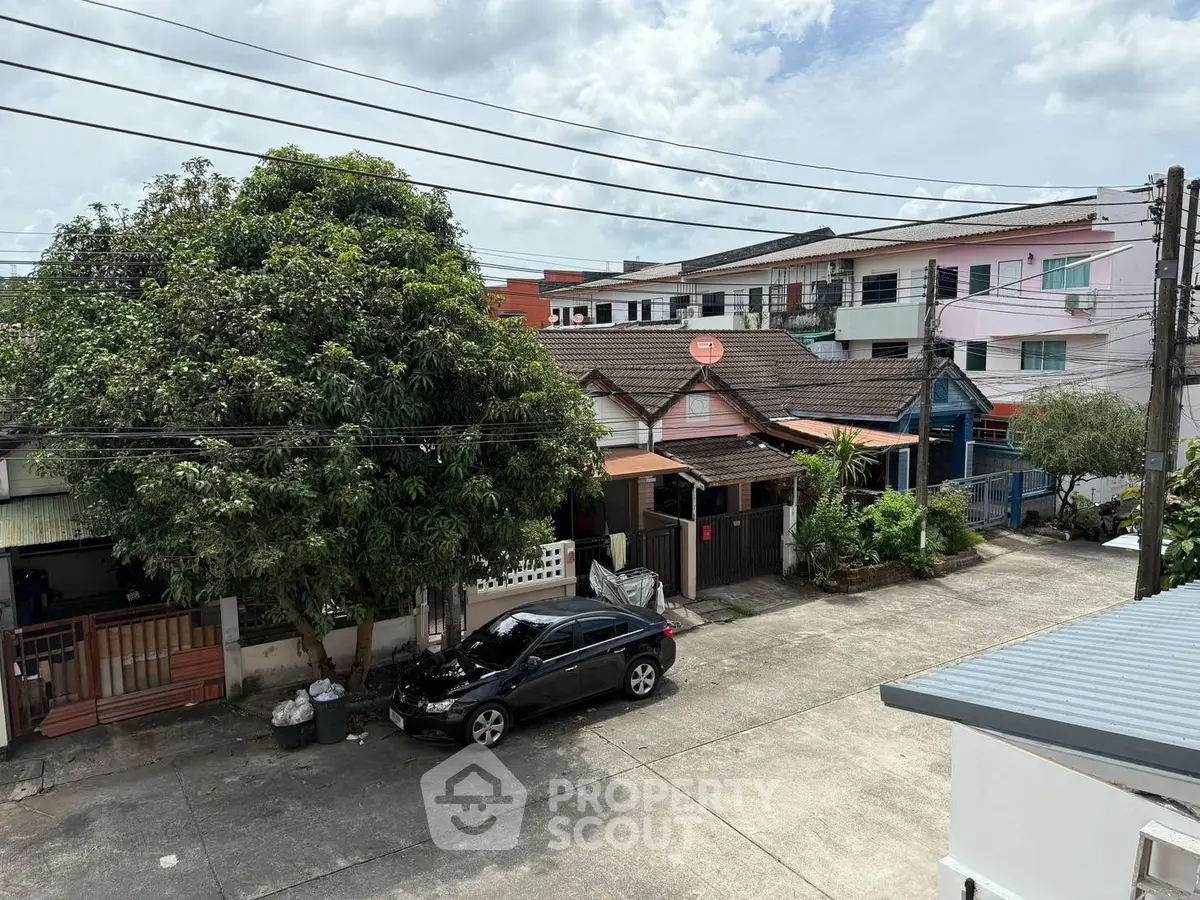 Charming residential street view with lush greenery and parked car.