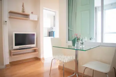 Charming modern living area with sleek glass table and cozy TV setup, perfect for urban living.