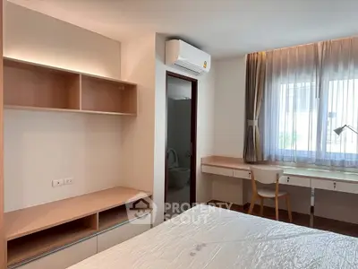 Modern bedroom with built-in shelves, desk, and air conditioning, featuring natural light from a large window.