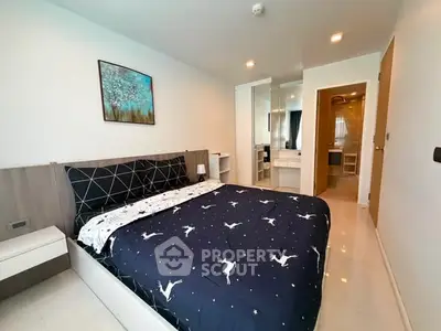 Modern bedroom with stylish decor and ensuite bathroom in a contemporary apartment.