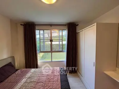 Cozy bedroom with large window and built-in wardrobe, offering natural light and garden view.