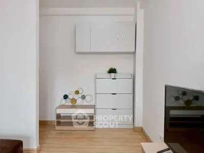 Modern minimalist living room with sleek white furniture and wooden flooring.