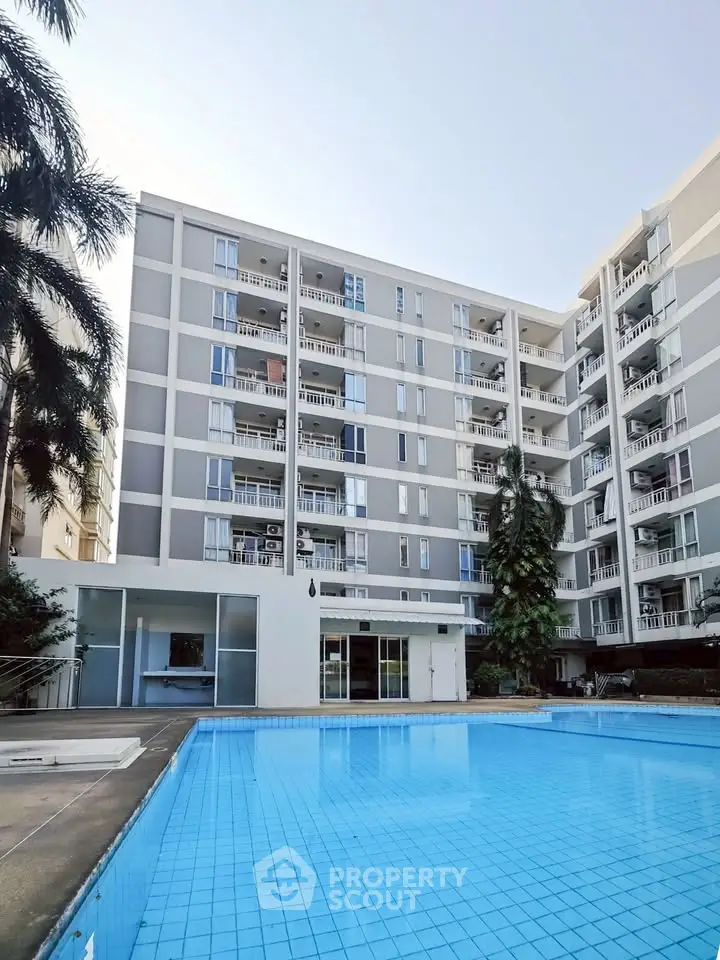 Modern apartment building with a pristine swimming pool and lush greenery.