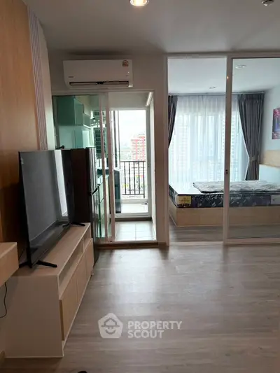 Modern apartment interior with open layout, featuring a cozy living room and bedroom with balcony access.