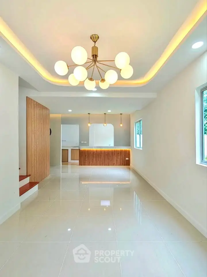 Modern living room with elegant lighting and open layout, featuring sleek flooring and natural light.
