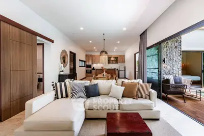 Spacious open-layout living room with modern kitchen and large sliding doors to balcony.