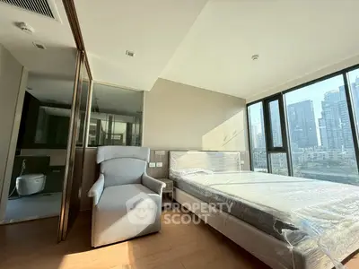 Modern bedroom with city view, featuring a single bed and armchair, perfect for urban living.