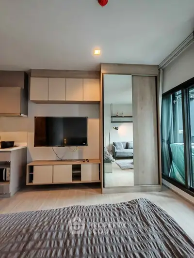 Modern living room with sleek TV unit and sliding door to cozy bedroom