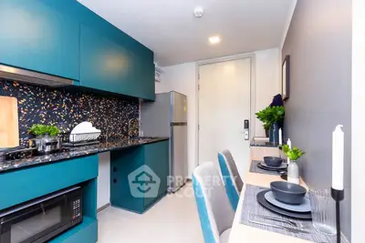 Modern kitchen with teal cabinets, sleek appliances, and stylish dining area in a contemporary apartment.