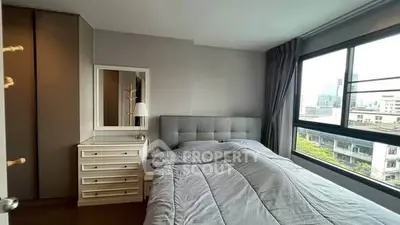 Modern bedroom with large window offering city view and stylish decor.