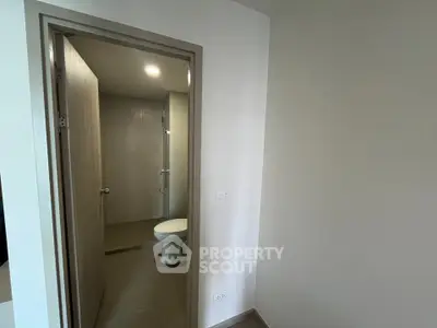 Modern bathroom with sleek design and neutral tones, featuring a shower and toilet in a compact space.