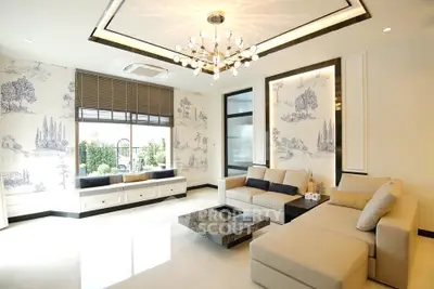 Luxurious living room with elegant chandelier and scenic wallpaper, featuring modern beige sofas and a marble coffee table.