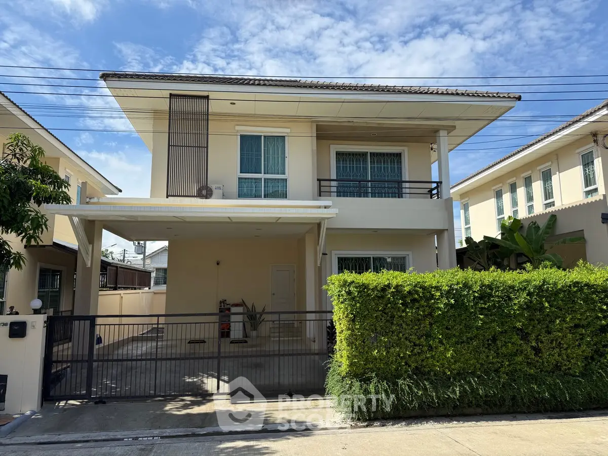 Charming two-story house with gated driveway and lush greenery