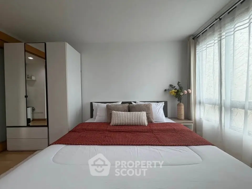 Spacious bedroom with modern decor and large window for natural light.