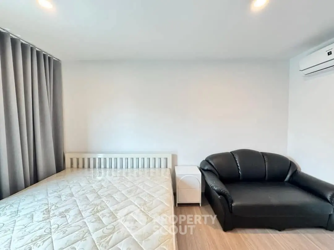 Modern bedroom with cozy sofa and air conditioning, featuring elegant curtains and stylish flooring.