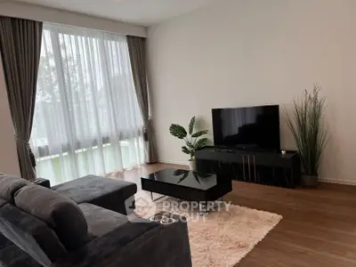 Elegant living room with modern decor and large windows, featuring a plush sofa and sleek TV setup.
