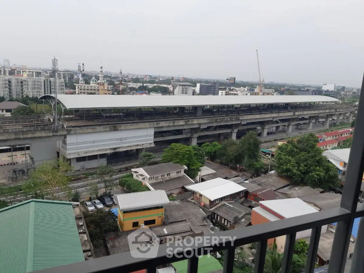 Urban cityscape view from balcony overlooking train station and residential area.