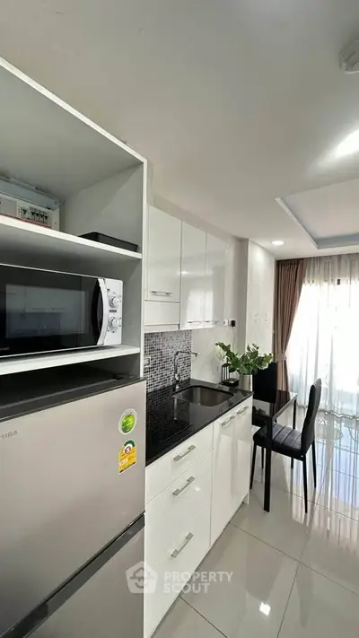 Modern kitchen with sleek white cabinets and stainless steel appliances in a bright apartment.