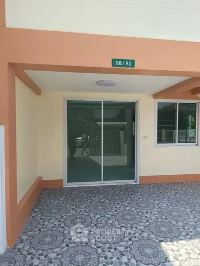 Modern exterior view of a residential property with sliding glass doors and patterned tile flooring.