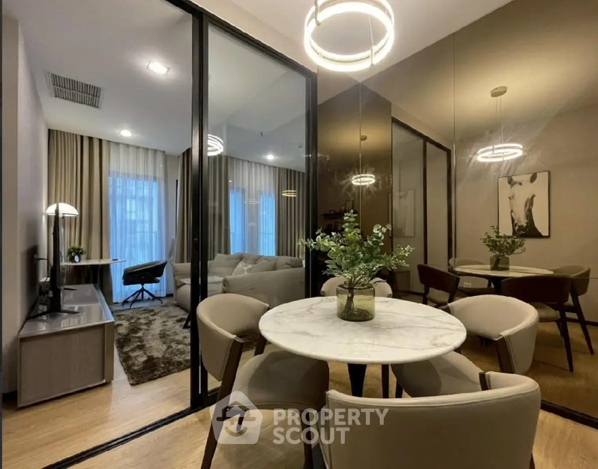 Modern dining area with marble table and stylish lighting in open-plan apartment.