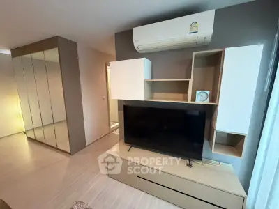 Modern living room with sleek TV unit and mirrored wardrobe, featuring air conditioning for comfort.