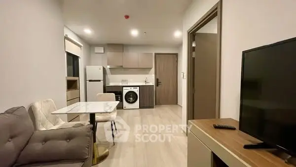 Modern open-plan living room and kitchen with sleek appliances and cozy seating area.