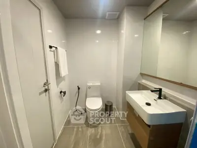 Modern bathroom with sleek fixtures and large mirror in contemporary apartment.