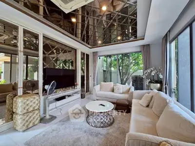 Luxurious living room with mirrored ceiling and elegant decor, featuring plush sofas and a stylish coffee table.