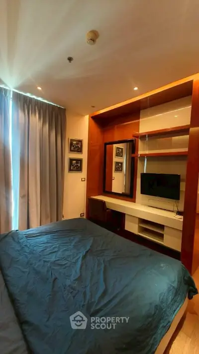 Modern bedroom with stylish decor and built-in TV unit, perfect for urban living.