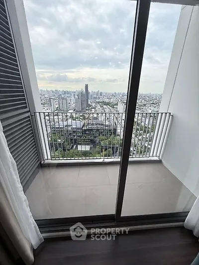 Stunning cityscape view from a modern high-rise balcony with glass doors and sleek design.