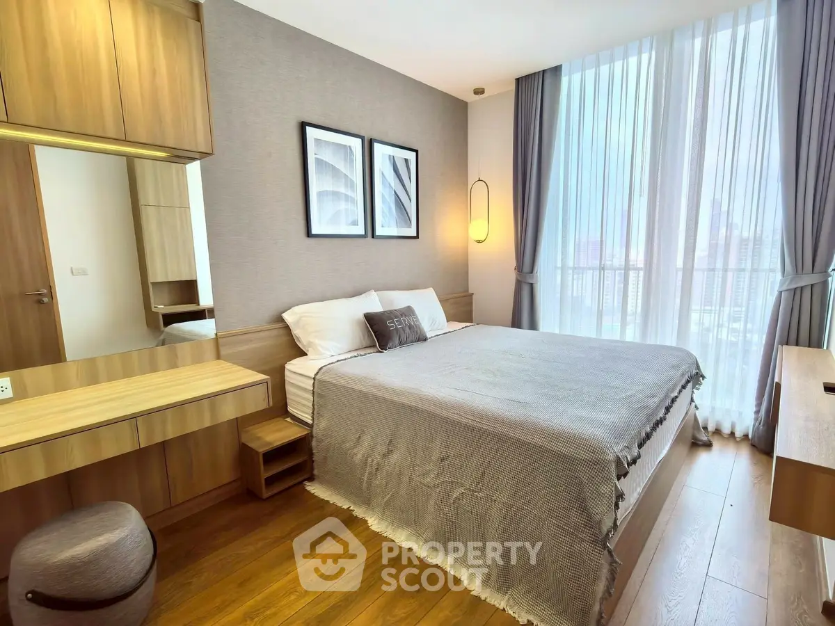 Modern bedroom with elegant decor and large window offering city views.