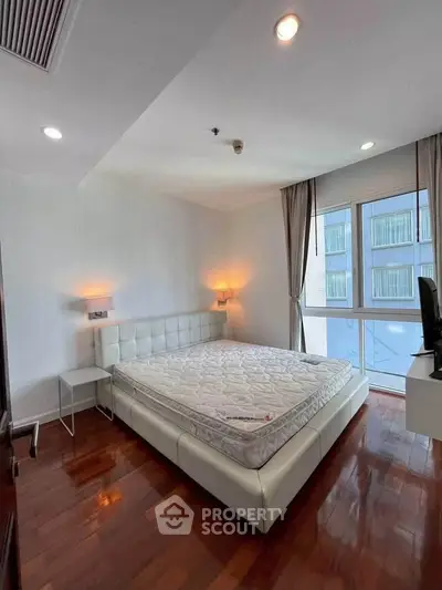 Spacious bedroom with modern decor and large window offering natural light.