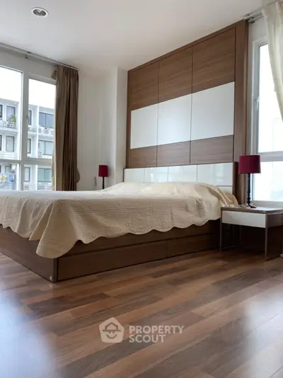 Modern bedroom with wooden flooring and large windows in a stylish apartment.