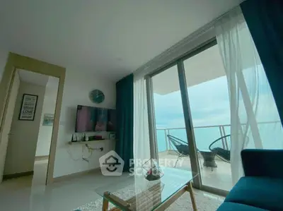 Modern living room with ocean view balcony, sleek furniture, and large glass doors.