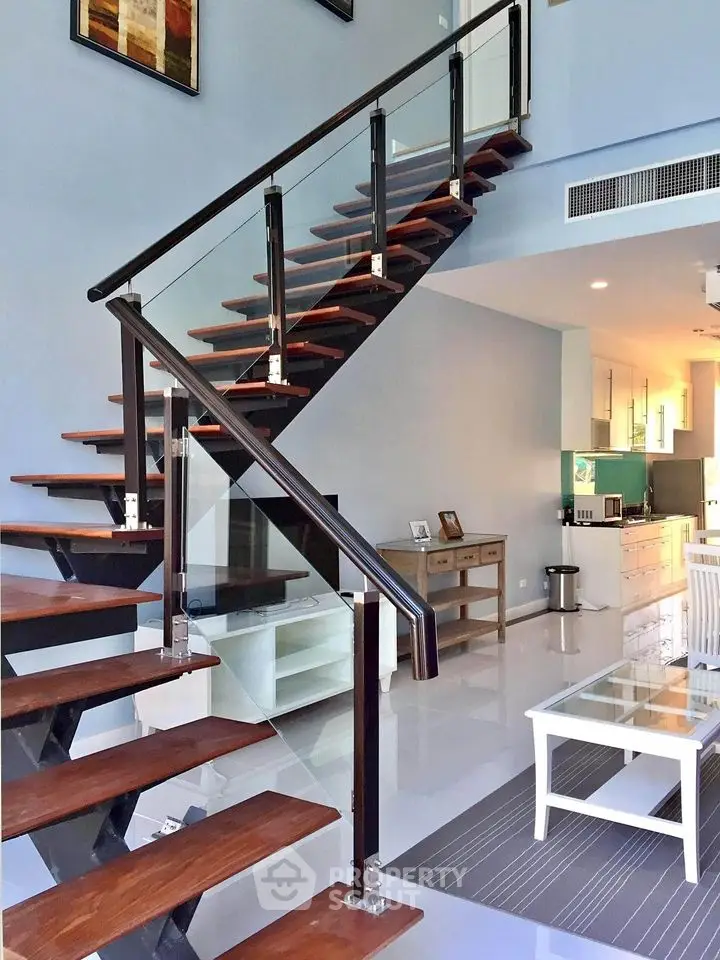 Modern open-plan living area with stylish staircase and sleek kitchen design.