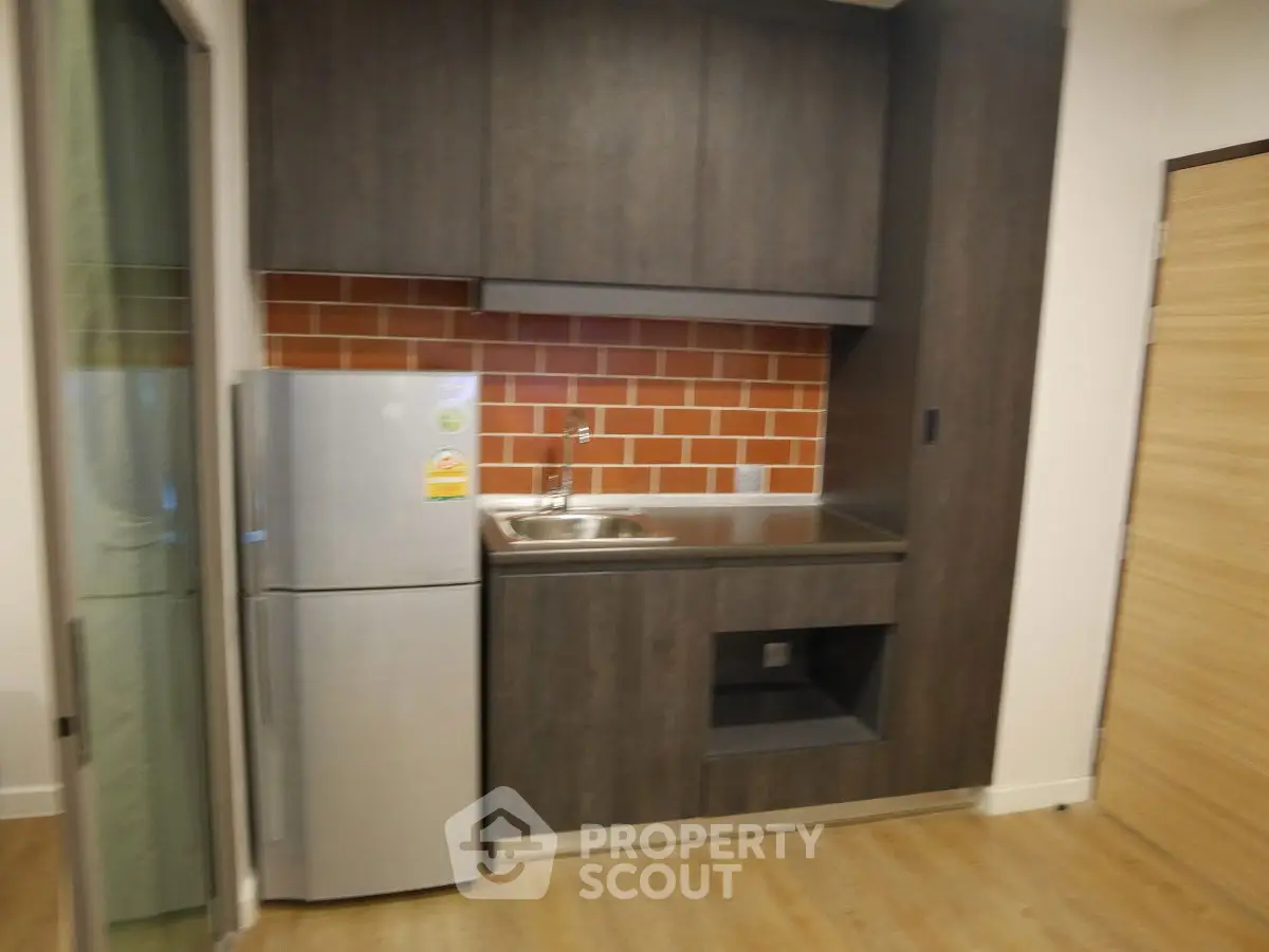 Modern compact kitchen with sleek cabinets and stainless steel fridge