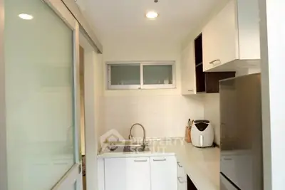 Compact modern kitchen with sleek white cabinets and stainless steel sink