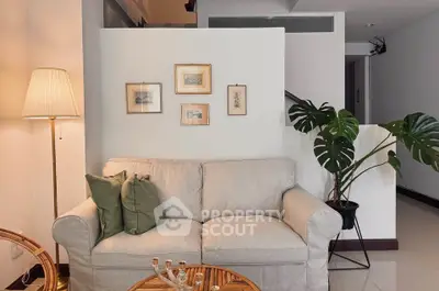 Cozy living room with elegant decor, featuring a comfortable sofa, stylish lamp, and framed art on the wall.