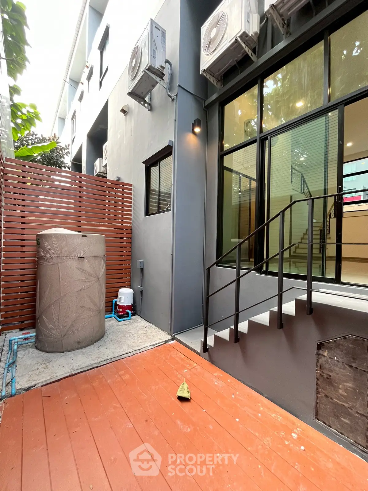Modern townhouse exterior with air conditioning units and wooden deck